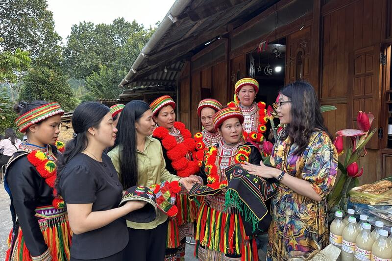 Giới thiệu cho du khách tham quan về sản phẩm thêu hoa văn trên trang phục người Dao Đỏ ( Tác giả: Hà Tuyết)
